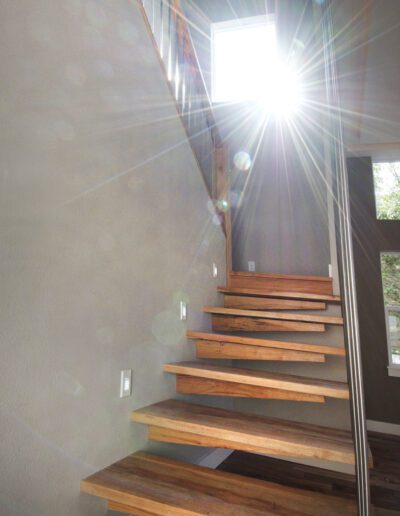 Sunlight streaming through a window at the top of a modern wooden staircase.