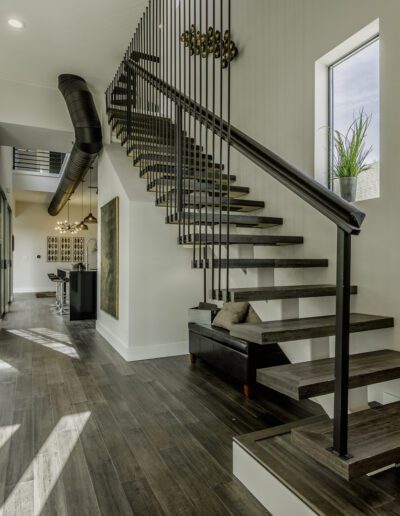 Modern home interior with high ceilings, floating staircase, and large windows.